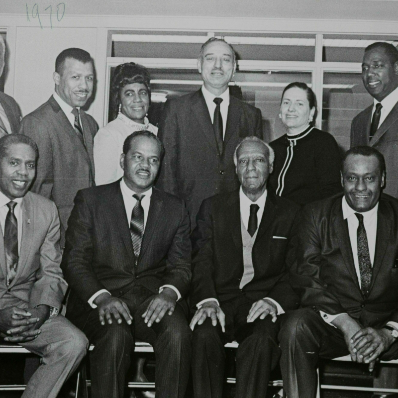 NAACP Members of the NAACP dressed in formal business attire pose for a picture. The front row is seated and the back row is standing behind them.